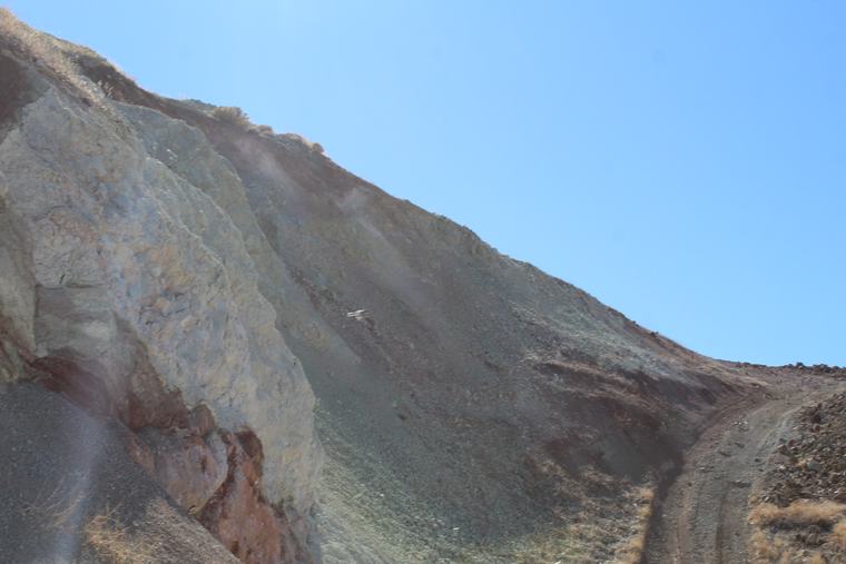 Pale skarn-textured rock exposed where the road cuts the hillside