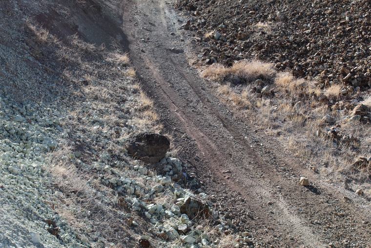 Pale greenish-grey rock in the road cut, range beyond
